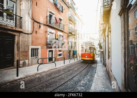 Une vue panoramique d'un tramway rétro rouge sur une rue étroite avec circulation ferroviaire à sens unique dans une ville européenne ; un tramway touristique vintage en rouge et jaune c Banque D'Images