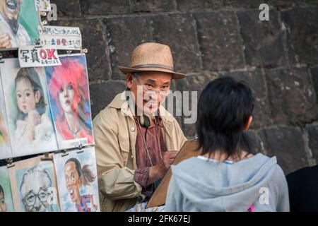 Une artiste japonaise âgée étudie une femme qui s'assoit en faisant dessiner son portrait à Ueno Park, Tokyo, Japon Banque D'Images