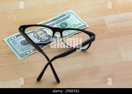 Lunettes à monture noire, lunettes sur 20 USD billet de banque argent facture se concentrant sur le visage, sur fond en bois Banque D'Images