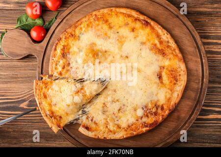 Prendre une tranche de pizza savoureuse à bord sur fond de bois Banque D'Images