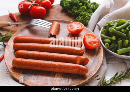 Assiette avec de savoureuses saucisses et légumes sur la table, gros plan Banque D'Images