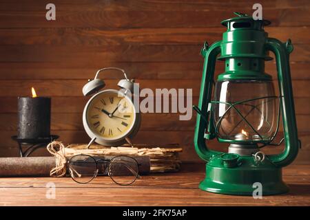 Lampe rétro élégante, réveil et lunettes sur fond de bois Banque D'Images