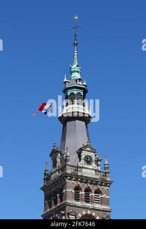 La tour de la Grande église dans la ville hollandaise d'Apeldoorn le jour national hollandais 'Koningsdag' (le jour du Roi), avec le drapeau national et le ruisseau orange. Banque D'Images