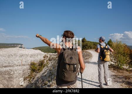 Deux randonneurs avec des sacs à dos et d'autres engins d'escalade restant au sommet du rocher. Homme pointant avec sa main discutant de la route. Plan, vision et mission concep Banque D'Images