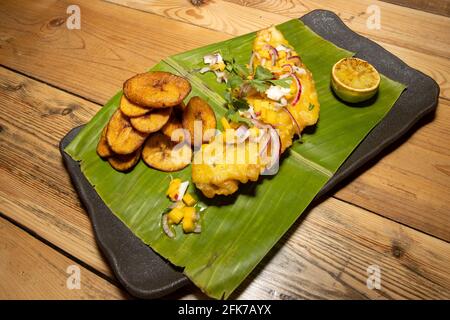 Un délicieux plat de poisson frit et d'inspiration ouest-africaine Frites avec tranches de banane frites servies sur une feuille de banane Banque D'Images