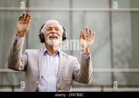 Portrait en plein air d'un homme d'affaires expérimenté qui profite de la musique avec un casque. Banque D'Images