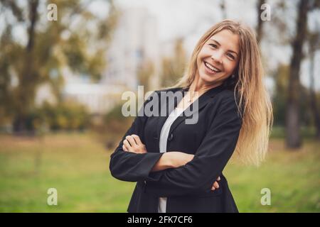 Portrait d'une femme d'affaires heureuse en plein air. Blonde femme d'affaires est debout à l'extérieur et souriant. Banque D'Images
