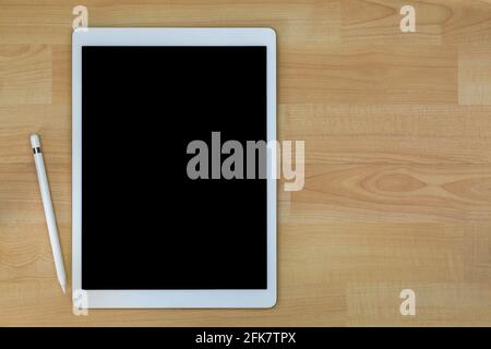 Tablette professionnelle blanche avec écran noir vierge à côté de crayon blanc sur fond en bois avec espace de copie Banque D'Images