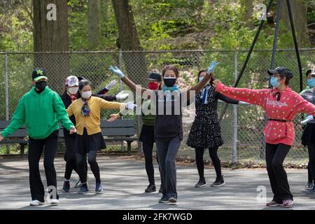 Les femmes américaines chinoises gracieuses portant un masque répètent avec un groupe de danse dans un parc à Queens, New York, leur maître est dans le haut rouge Banque D'Images