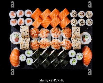 Cuisine orientale japonaise. Du dessus de la plaque de pierre avec un grand ensemble de délicieux sushis Nigiri et un assortiment de rouleaux d'uramaki avec du poisson et des légumes frais Banque D'Images