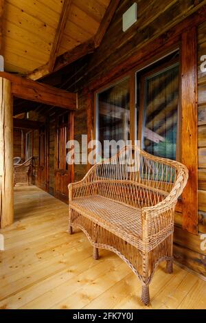 Vue latérale sur un banc en rotin sur la terrasse extérieure d'un cottage. Banque D'Images