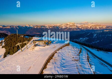 Prise de vue aérienne d'une station de remontée mécanique au sommet d'une montagne enneigée au lever/coucher du soleil. Banque D'Images