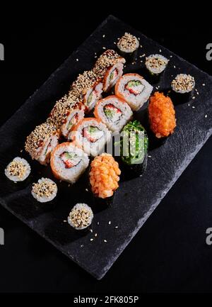 Sushi japonais. Des petits pains Maki and au thon, au saumon, aux crevettes, au crabe et à l'avocat sont servis sur une ardoise de pierre. Vue de dessus de l'assortiment de sushis. Sushis arc-en-ciel Banque D'Images