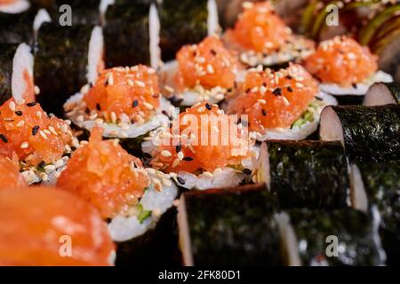 Gros plan sur le rouleau maki avec du saumon frais, des concombres et des graines de sésame. Concept alimentaire japonais. Banque D'Images
