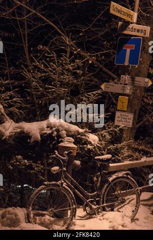 Des panneaux de rue et un vélo sur une nuit enneigée à Füssen, au sud de l'Allemagne. Banque D'Images