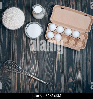 Ingrédients de gâteau à cuire: Farine, sucre, oeufs sur un bureau en bois, plat Banque D'Images