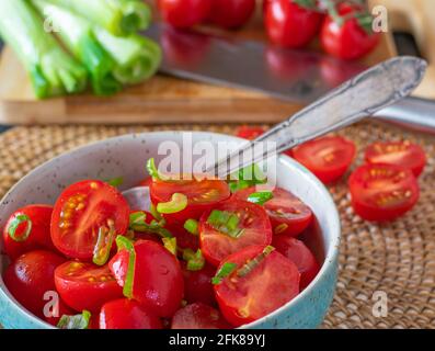 Un bol de salade de tomates fraîchement préparée avec de la ciboulette et de l'huile d'olive servi sur une table de cuisine. Vue en gros plan Banque D'Images