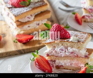 Un morceau de gâteau frais à la crème de fraise sur une assiette avec un fond rustique de table en bois Banque D'Images