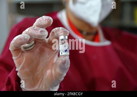 Infirmière à l'intérieur de la pharmacie tout en préparant une seringue pour l'administration du vaccin astrazeneca.Détail du flacon contenant le vaccin. Banque D'Images