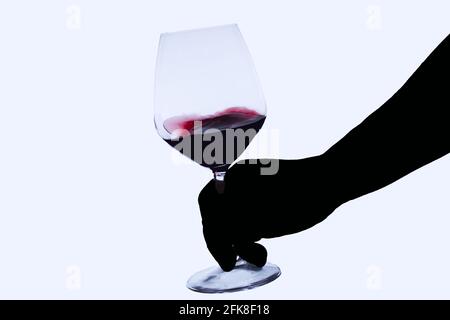 silhouette du bras d'un sommelier tenant un verre divin tout en le faisant tourner avec effet de flou, isolé sur fond blanc Banque D'Images