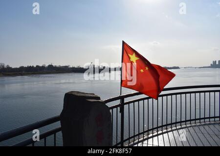 Drapeau chinois ordonnant au-dessus de la rivière à la frontière entre la Chine et la Corée du Nord [pont de la rivière Yalu Broken, Dandong, Chine, 1er décembre 2016] Banque D'Images