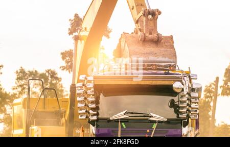 Pelle rétro travaillant en creusant le sol sur le chantier et en le chargeant sur le tombereau. Le godet de la pelle rétro transporte le sol vers le camion. La pelle sur chenilles décharge la saleté Banque D'Images