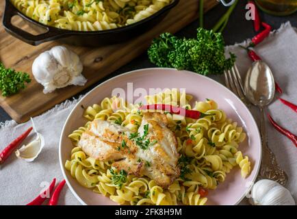 Plat italien sain avec pâtes aglio e olio et frit poisson servi sur l'assiette sur le fond rustique de la table de cuisine de ci-dessus Banque D'Images