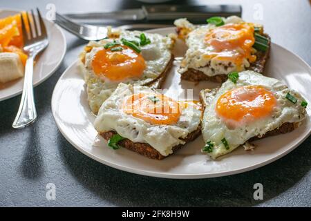 Une assiette de sandwichs à surface ouverte surmontée d'une friture fraîche oeufs et ciboulette isolés sur une table à la maison Banque D'Images