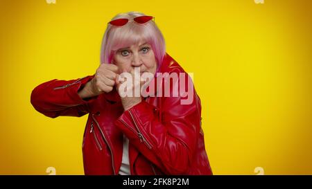 Drôle de femme granny senior essayant de se battre à la caméra, secouant poing, boxe avec punition d'expression Banque D'Images