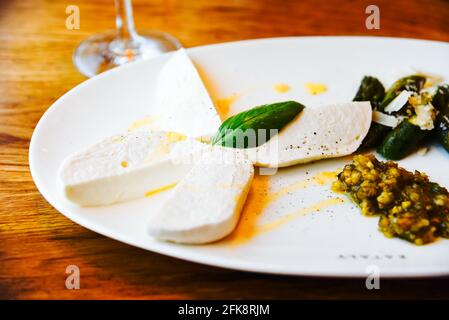 Délicieuse salade de mozzarella avec légumes et huile d'olive sur un une assiette joliment décorée dans un restaurant par un chef renommé Banque D'Images