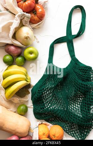 Faites des légumes et des fruits sains et colorés avec un sac en filet vert dans la partie droite de la scène sur un fond blanc. Banque D'Images