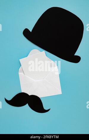 carte de fête des pères, composition avec chapeau noir, moustache et enveloppe avec espace vide pour le texte isolé sur fond bleu Banque D'Images