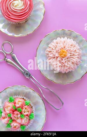 gâteaux de tasse colorés décorés de glaçage sur fond rose, parfaits pour une cuisine, un poster pédagogique ou un décor Banque D'Images