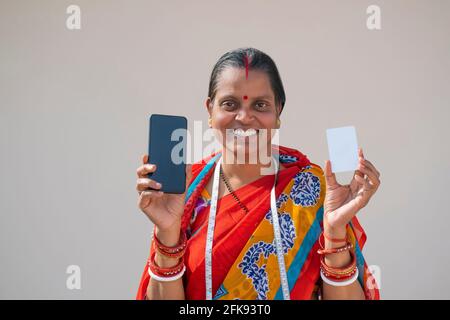 PORTRAIT D'UNE FEMME RURALE TENANT UN TÉLÉPHONE PORTABLE ET UNE CARTE Banque D'Images