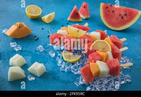 Brochettes de melon sur glace sur fond bleu Banque D'Images