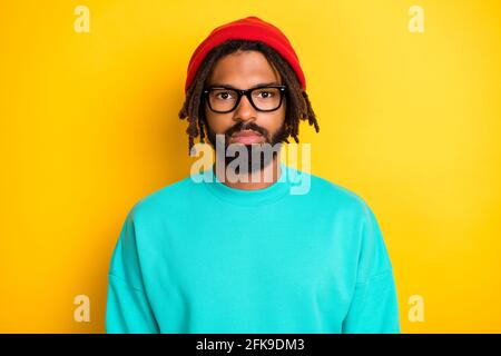 Photo du jeune homme beau africain sérieux confiant porter des lunettes isolé sur fond jaune Banque D'Images