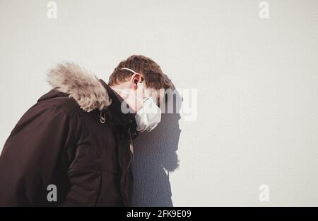 Jeune homme européen en masque médical jetable de protection près du mur. Peur du dangereux N-COV 2019 virus de la grippe coronavirus. Banque D'Images