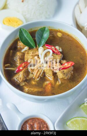 Rawon est une soupe traditionnelle noire de bœuf indonésien. Servi avec du riz à la vapeur, de l'oeuf salé, des pousses de haricots, des sambal et du krupuk (crackers de crevettes) Banque D'Images