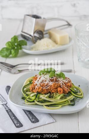 Zoodles bolognese: Nouilles courgettes avec viande ou sauce à la viande de soja végétalienne et parmesan. Pour une alimentation faible en glucides, keto et paléocarbe. Photo de stock verticale. Banque D'Images