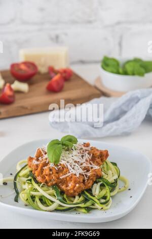 Zoodles bolognese: Nouilles courgettes avec viande ou sauce à la viande de soja végétalienne et parmesan. Pour une alimentation faible en glucides, keto et paléocarbe. Photo de stock verticale avec cop Banque D'Images