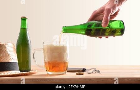 Servir dans une tasse à bière avec une bouteille et un chapeau arrière-plan isolé de table en bois Banque D'Images