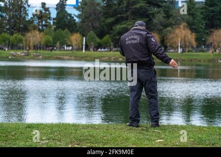 policier parlant au téléphone contre l'arrière-plan du lac Banque D'Images