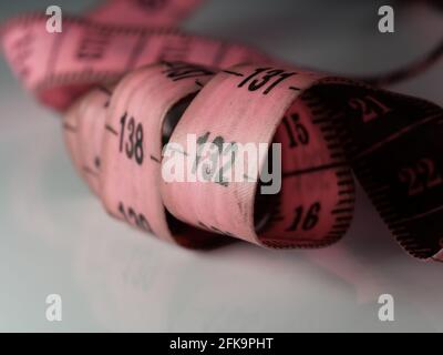 Gros plan ruban de mesure sur mesure sur fond de table blanc. Ruban de mesure blanc faible profondeur de champ. Macro. Banque D'Images