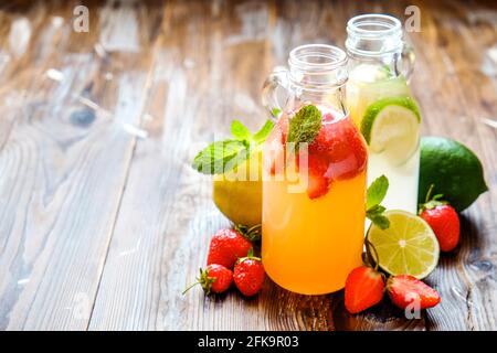 Trois bouteilles millésimes fraîches de limonade glacée, boissons aux goûts différents avec citron, orange, pamplemousse, citron vert, feuilles de menthe et fraise sur la courge grachée Banque D'Images