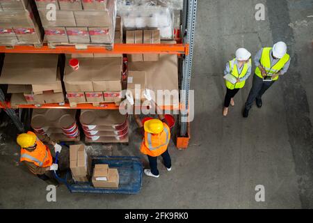 Directement au-dessus de la vue des travailleurs de la réserve dans les gilets réfléchissants et casques de sécurité qui interagissent entre eux lors de la distribution de marchandises Banque D'Images