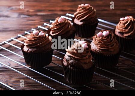 Délicieux cupcakes au chocolat noir, garniture en coeur de sucre, table texturée en bois. Boulangerie cacao, grille rustique étagère café-restaurant hippster table Banque D'Images