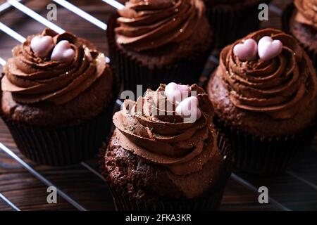 Délicieux cupcakes au chocolat noir, garniture en coeur de sucre, table texturée en bois. Boulangerie cacao, grille rustique étagère café-restaurant hippster table Banque D'Images