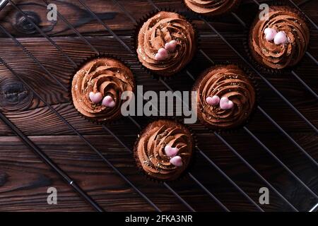 Délicieux cupcakes au chocolat noir, garniture en coeur de sucre, table texturée en bois. Boulangerie cacao, grille rustique étagère café-restaurant hippster table Banque D'Images