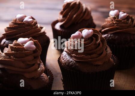 Délicieux cupcakes au chocolat noir, garniture en coeur de sucre, table texturée en bois. Boulangerie au cacao, café rustique en tranches d'arbre en bois, tabl de l'hippopotame Banque D'Images