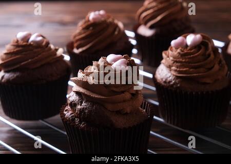 Délicieux cupcakes au chocolat noir, garniture en coeur de sucre, table texturée en bois. Boulangerie cacao, grille rustique étagère café-restaurant hippster table Banque D'Images